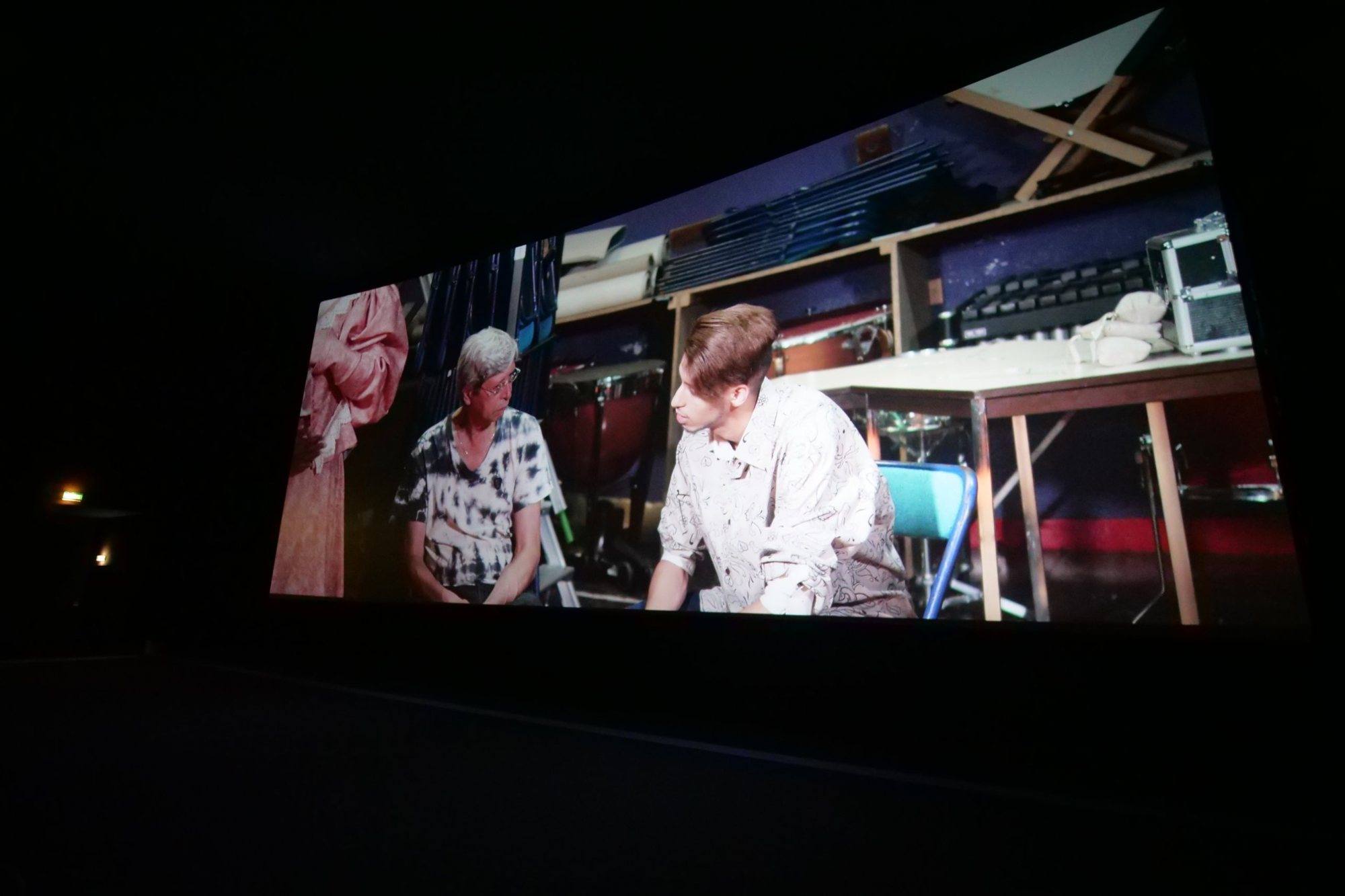 Still from the film: a young man and a woman sitting backstage in a theater