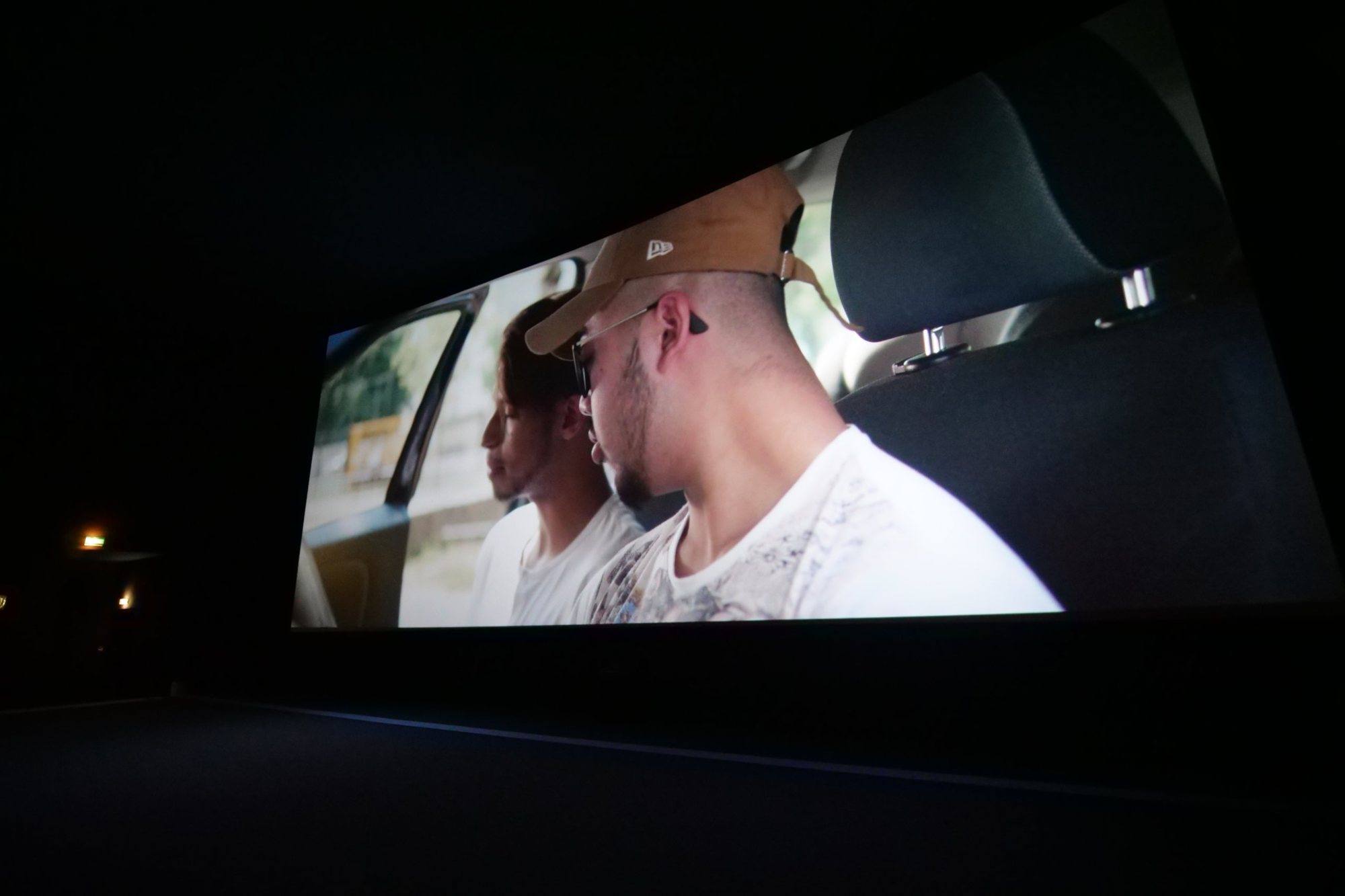 Still from the film: two young men in the back seat of a car
